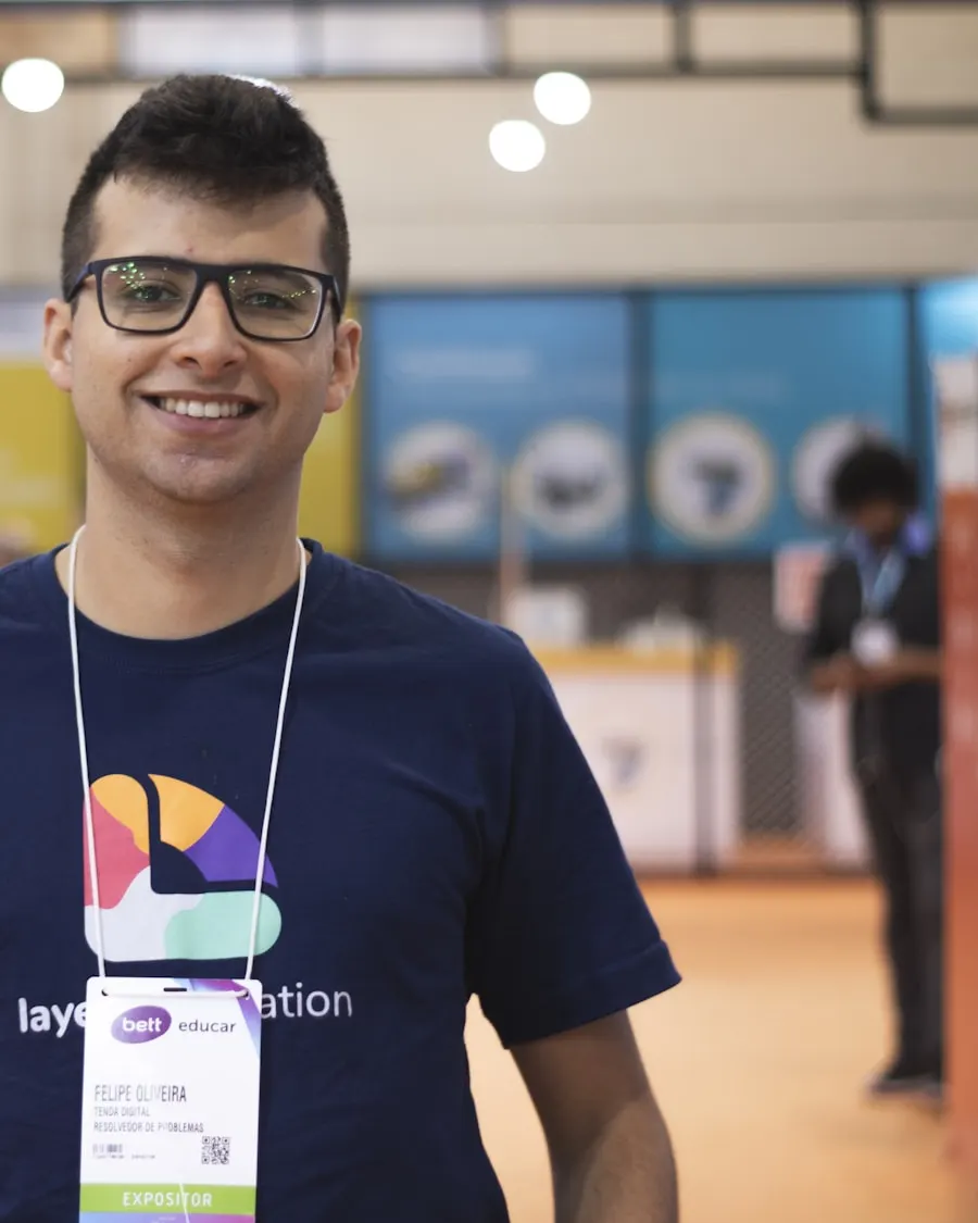 Retrato de um jovem sorridente de t-shirt e credencial num evento.