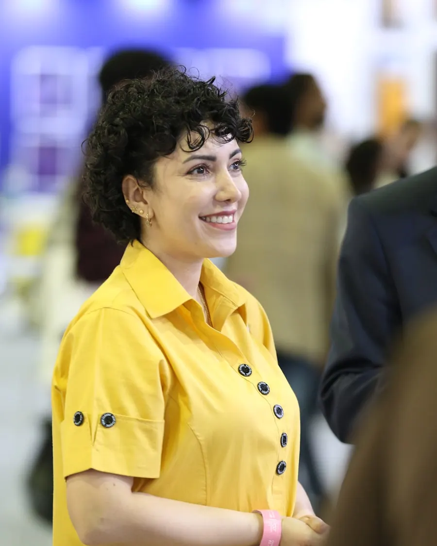 Una mujer con camisa amarilla sonríe en un evento.